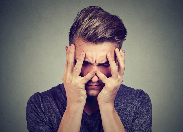 Der Mann hält sich die Hände ans Gesicht und wirkt gestresst.