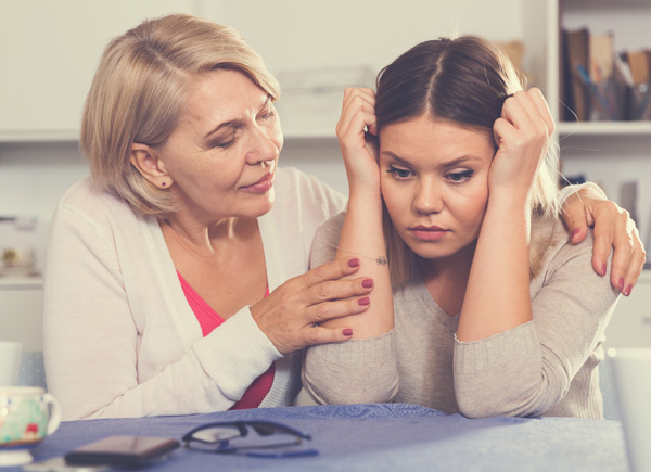 Das Bild zeigt eine ältere Frau, die eine jüngere Frau tröstet.